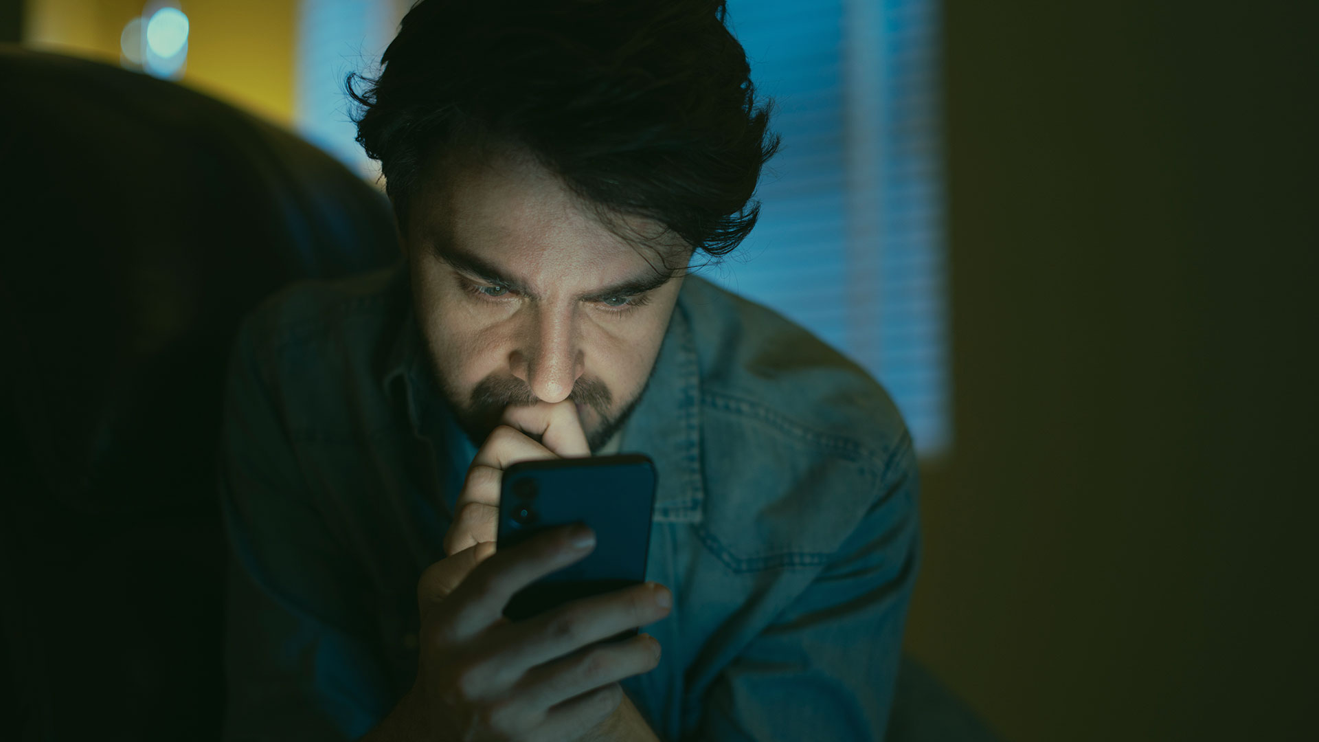 Man looking intently at his phone late at night