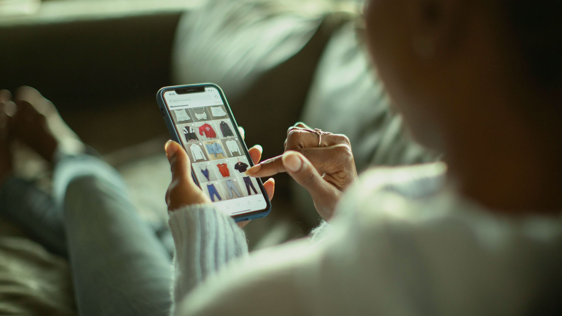 Person browsing a shopping app on the sofa