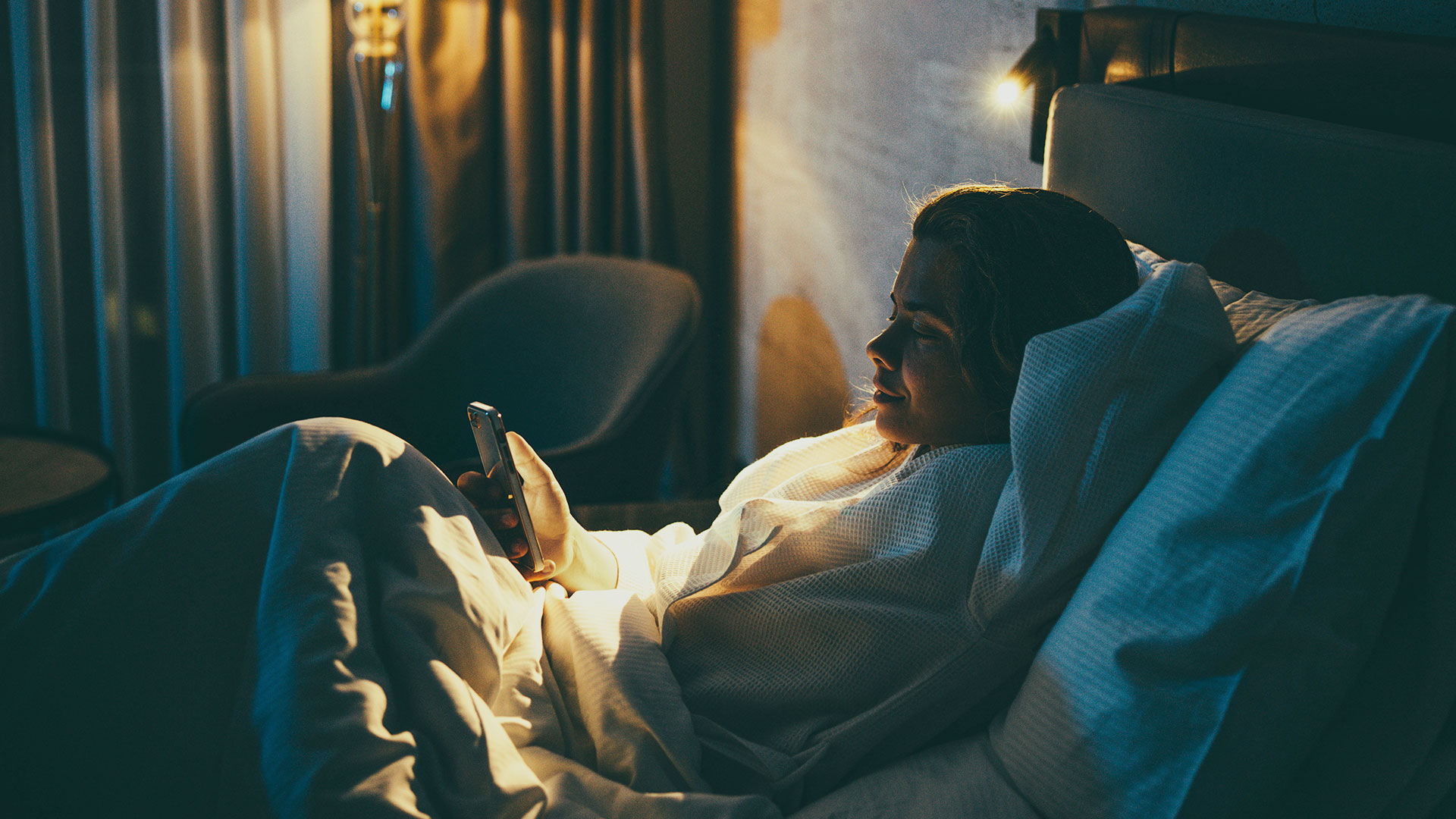 Woman using her phone in a dark bedroom