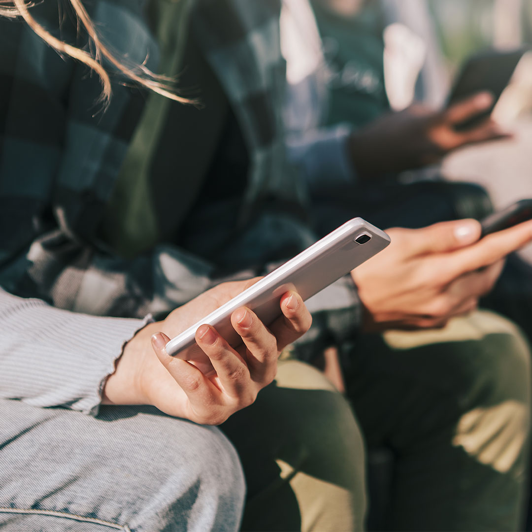 Young people casually using their phones together outdoors